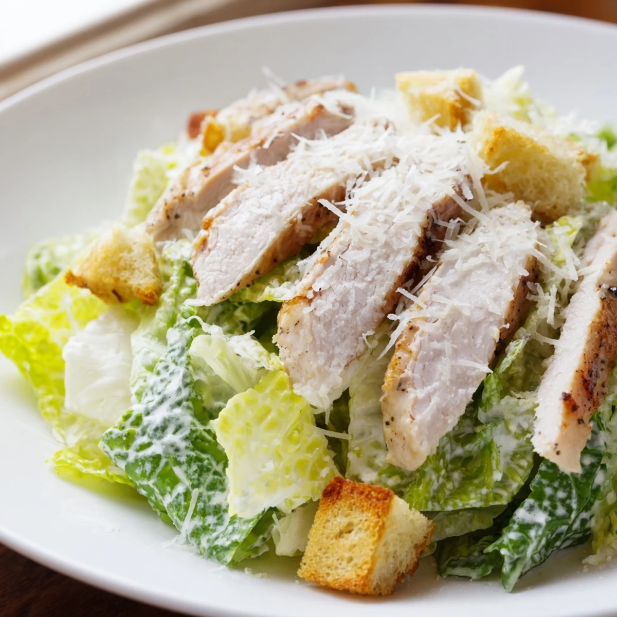 Golden homemade croutons add crunch to a vibrant bowl of Chicken Caesar Salad, drizzled with creamy dressing.