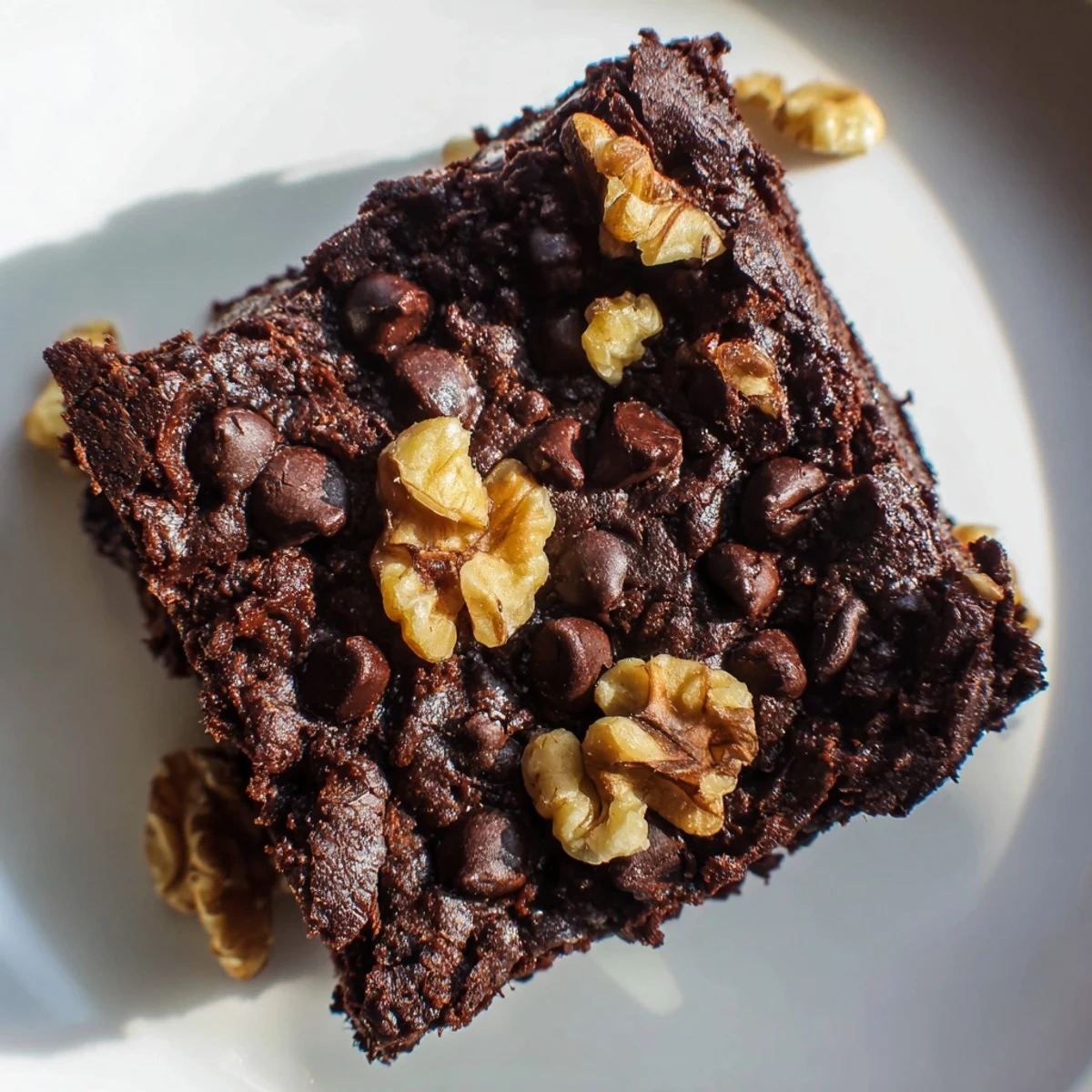 Plated Chocolate Fudge Brownies with Chopped Walnuts served warm with melting vanilla ice cream and a drizzle of chocolate sauce.