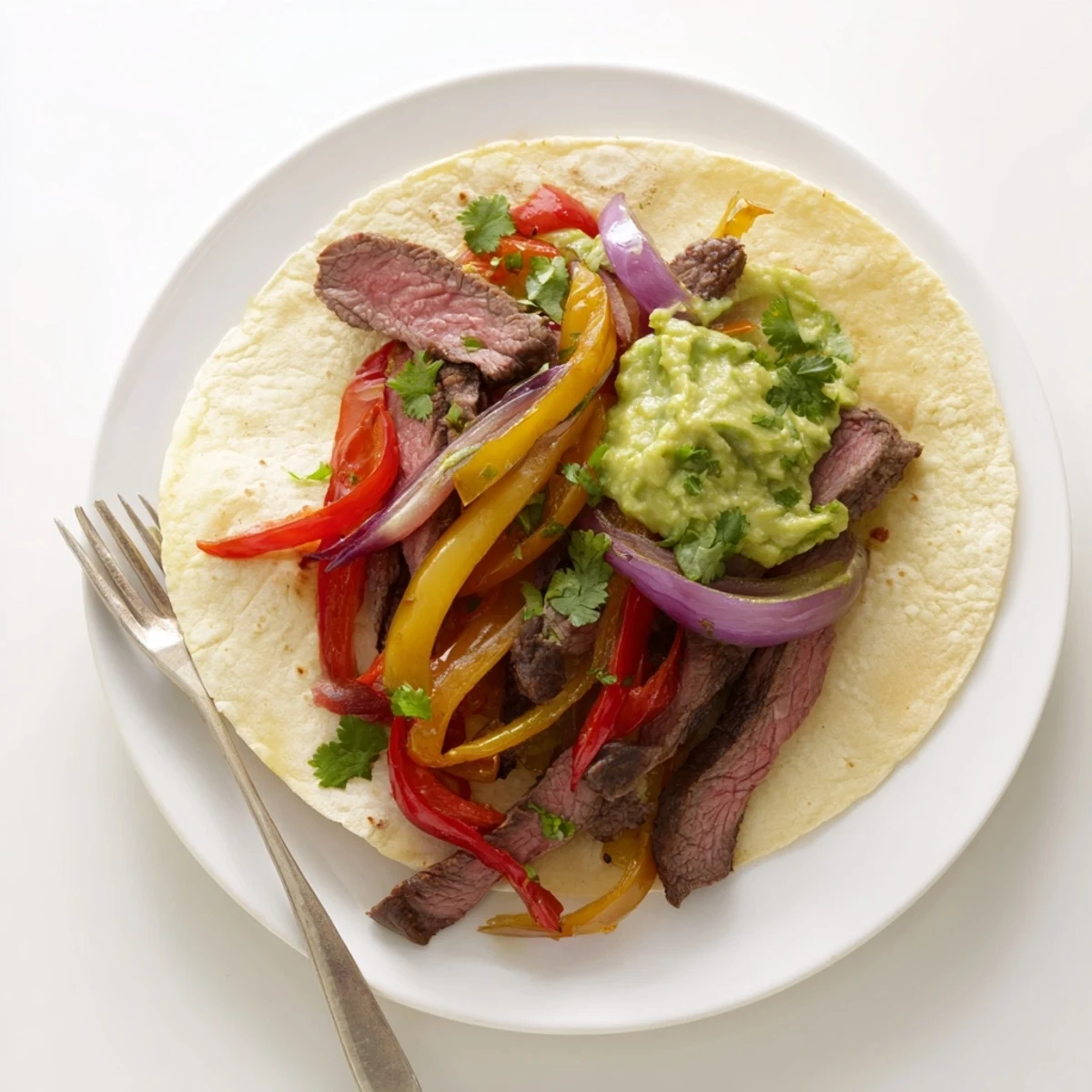 Homemade Beef Fajitas with tender marinated steak, vibrant sautéed vegetables, and a dollop of chunky guacamole, ready to be wrapped and enjoyed for a family dinner.