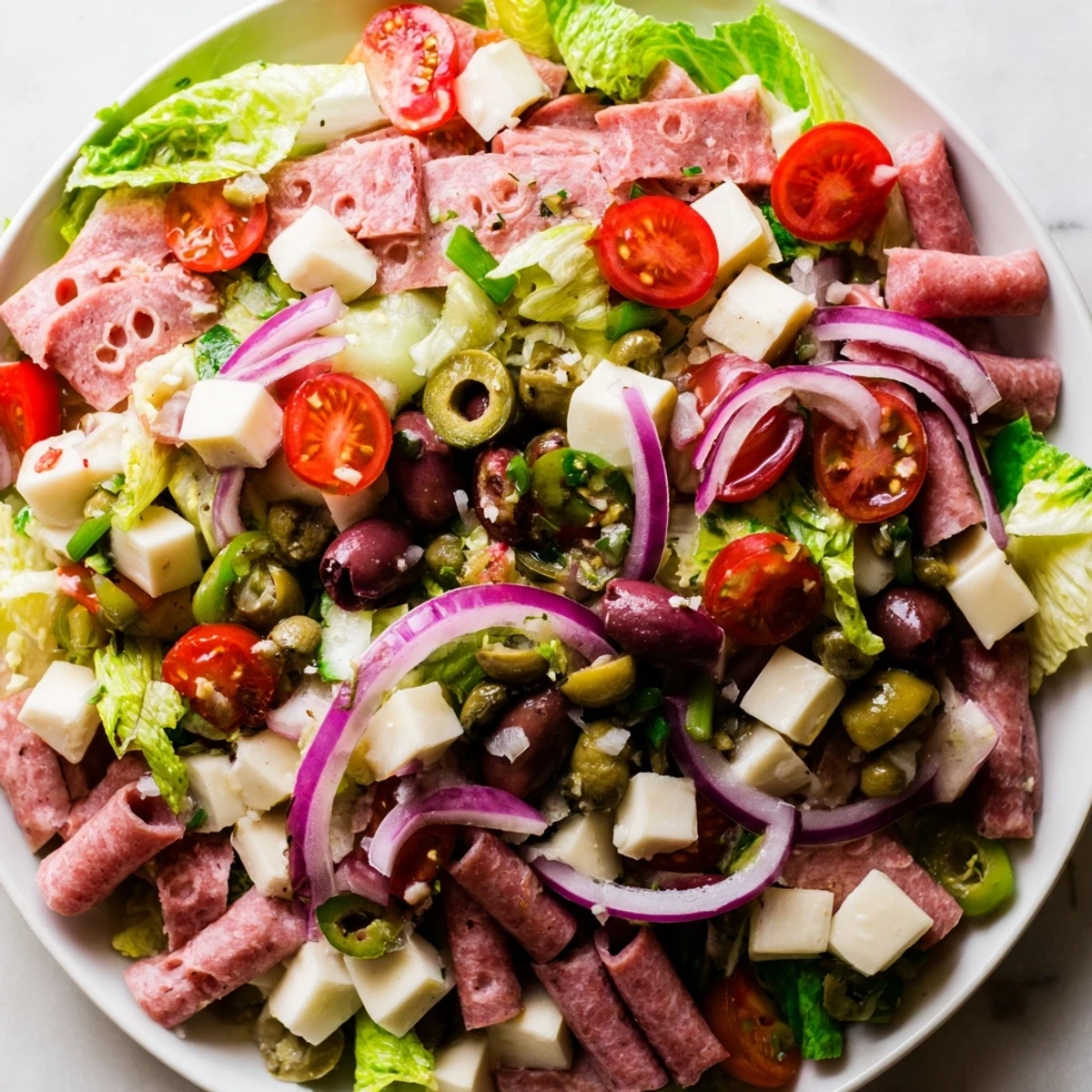 Tossed New Orleans Muffuletta Salad with colorful vegetables, olives, and meats, ready for a flavorful lunch or picnic.