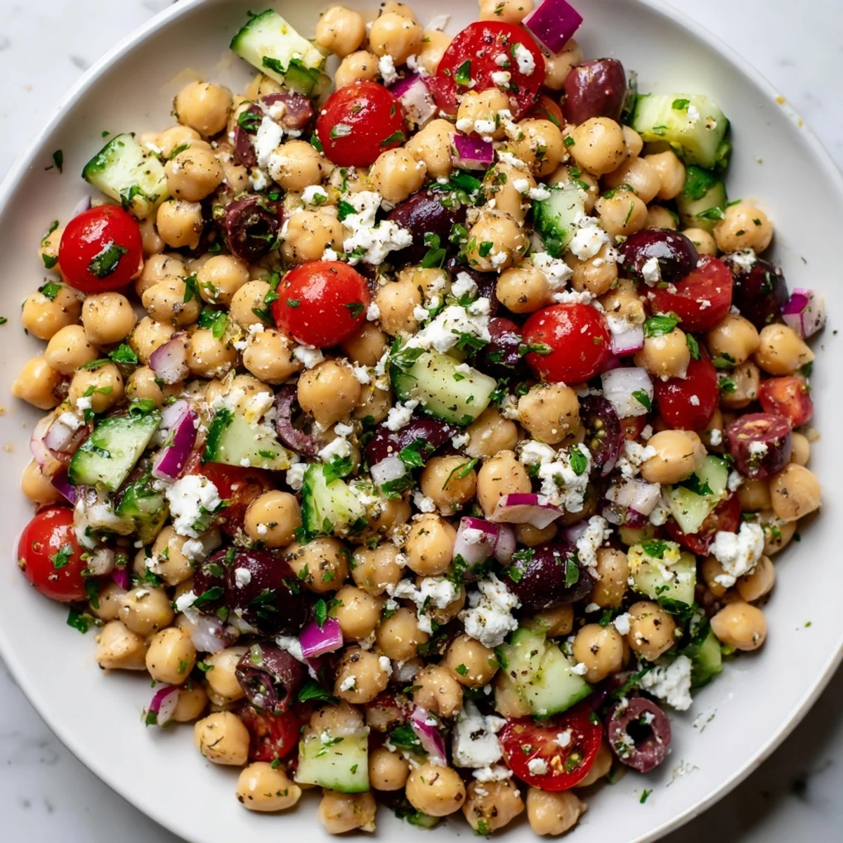 Tasty Mediterranean Chickpea Salad with Feta served on a wooden board with fresh parsley and lemon wedges nearby.