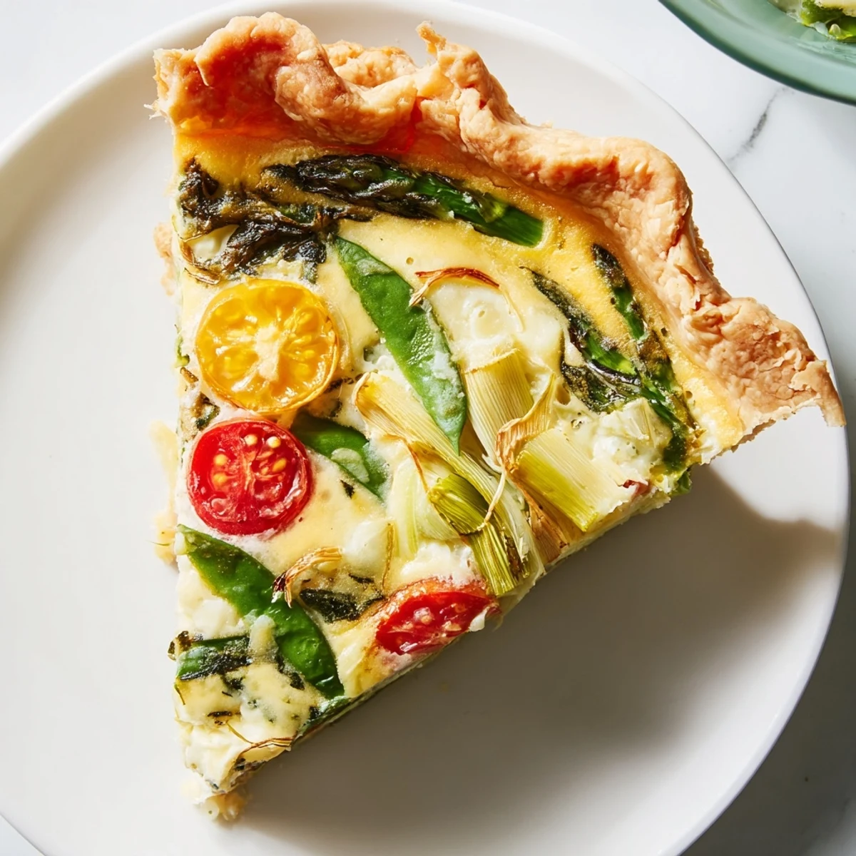 Sliced Spring Vegetable Quiche with Crust rests on a plate beside a green salad for a light lunch.