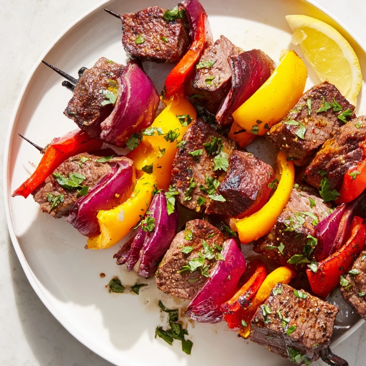 Close-up of juicy Beef Kebabs with Bell Peppers and Red Onion on a platter with parsley garnish.
