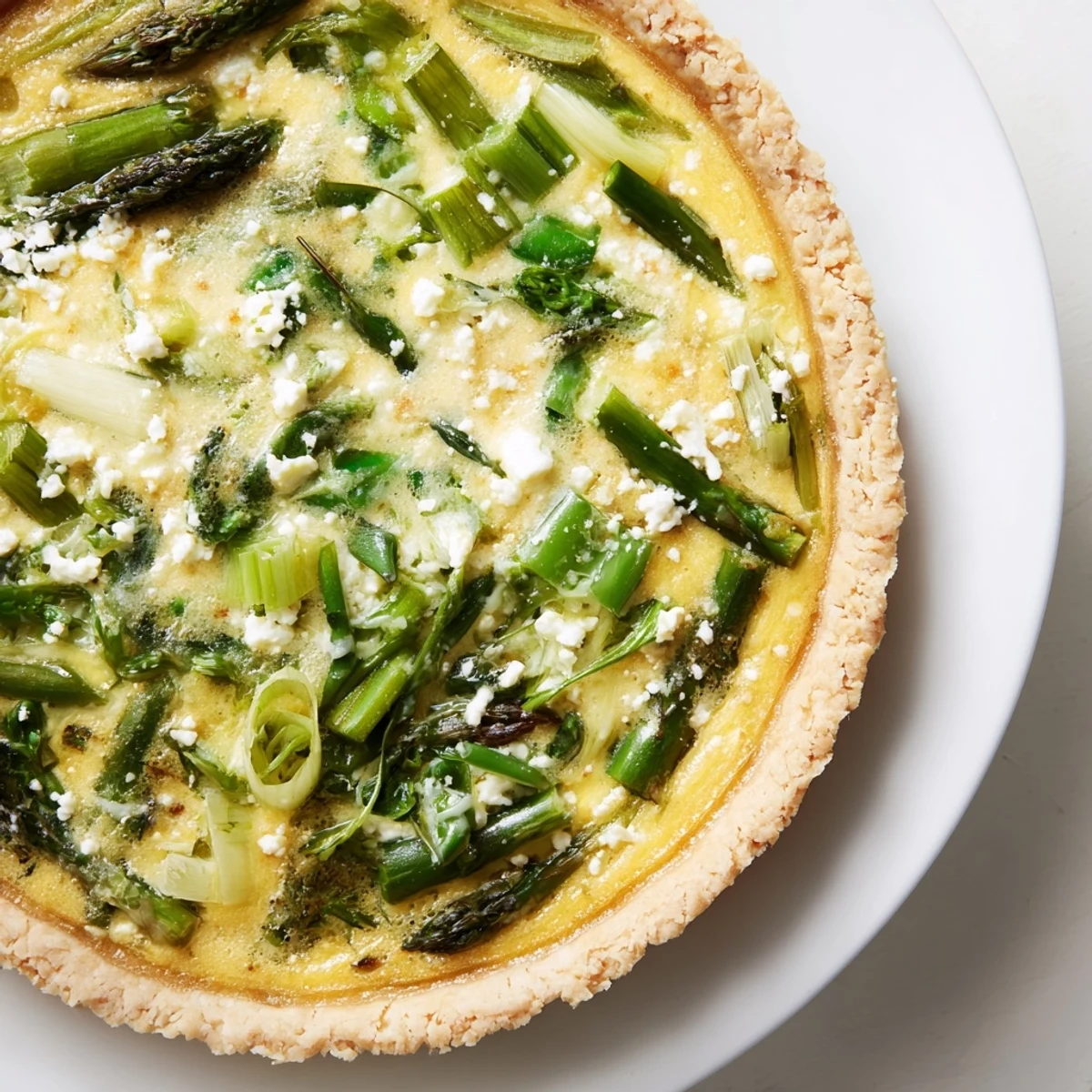 Flaky crust of a Spring Vegetable Quiche with tender leeks and asparagus, served warm for a light lunch.