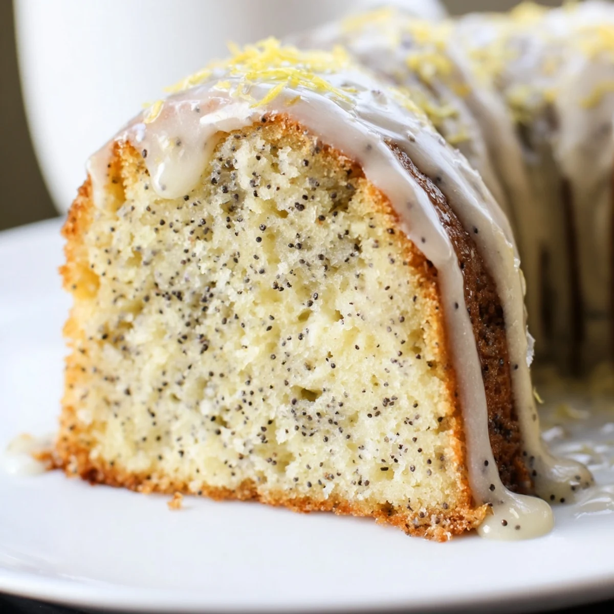 A close-up view of the moist, zesty Lemon Poppy Seed Bundt Cake with Icing, highlighting the crunchy poppy seeds and glossy lemon glaze.