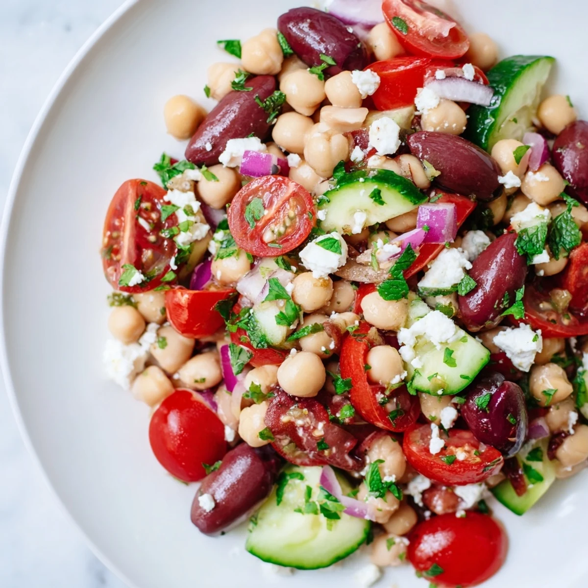 Close-up of Mediterranean Dense Bean Salad with colorful beans, cucumber, and olives glistening with dressing.