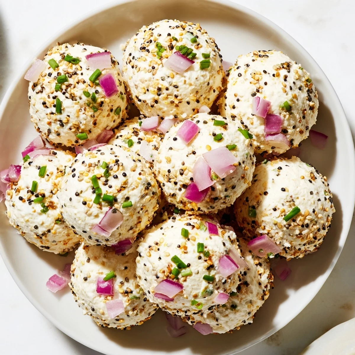 Freshly rolled Everything Bagel Cottage Cheese Bites coated in sesame and poppy seeds on marble.