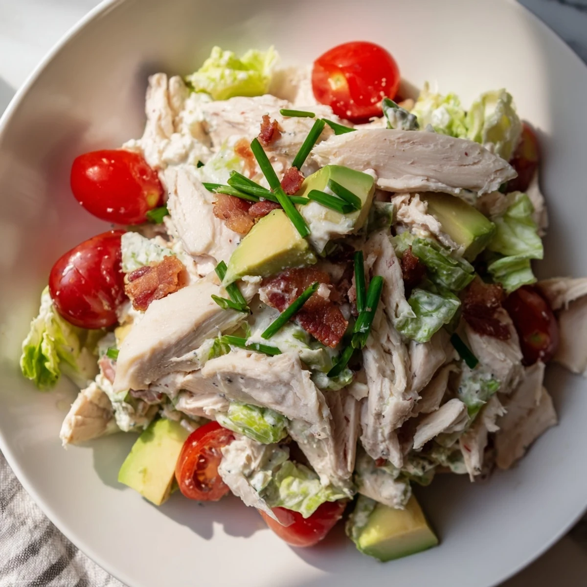 Crispy bacon and juicy sliced chicken fill a colorful bowl of romaine, cherry tomatoes, and avocado in this BLT Chicken Salad.
