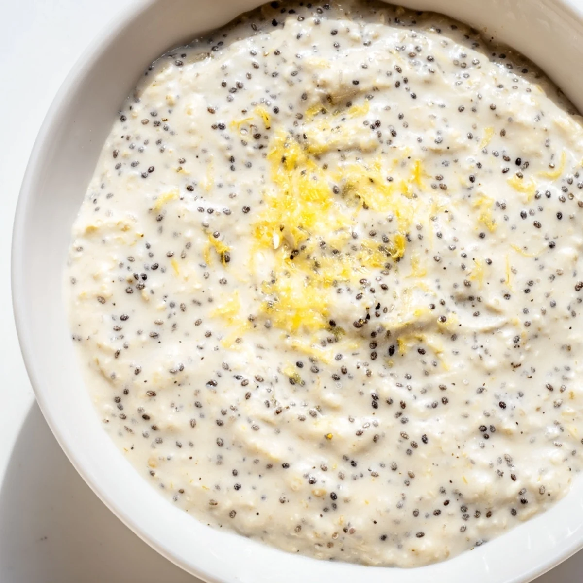 Creamy Vegan Lemon Poppy Seed Overnight Oats with fresh berries and sliced almonds in a glass jar.