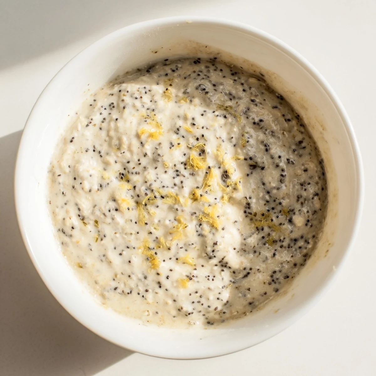 Thick Vegan Lemon Poppy Seed Overnight Oats topped with coconut yogurt and a lemon zest garnish.