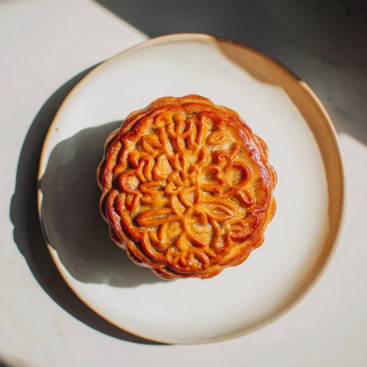 Twelve beautifully crafted mooncakes are displayed on a white plate, ready to be served with a cup of Chinese tea.