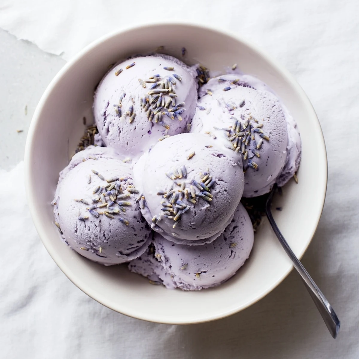 Serving suggestion of Lavender Ice Cream in elegant dessert bowls, topped with dried lavender buds, perfect for a refreshing French-inspired summer treat.