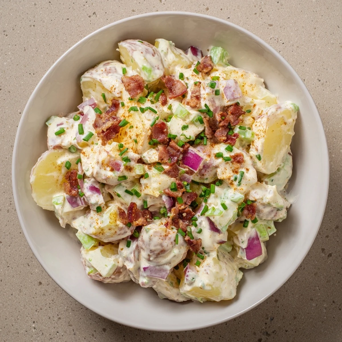 Hearty steakhouse potato salad with tangy Dijon dressing, crunchy celery, and scallions in a rustic serving bowl.
