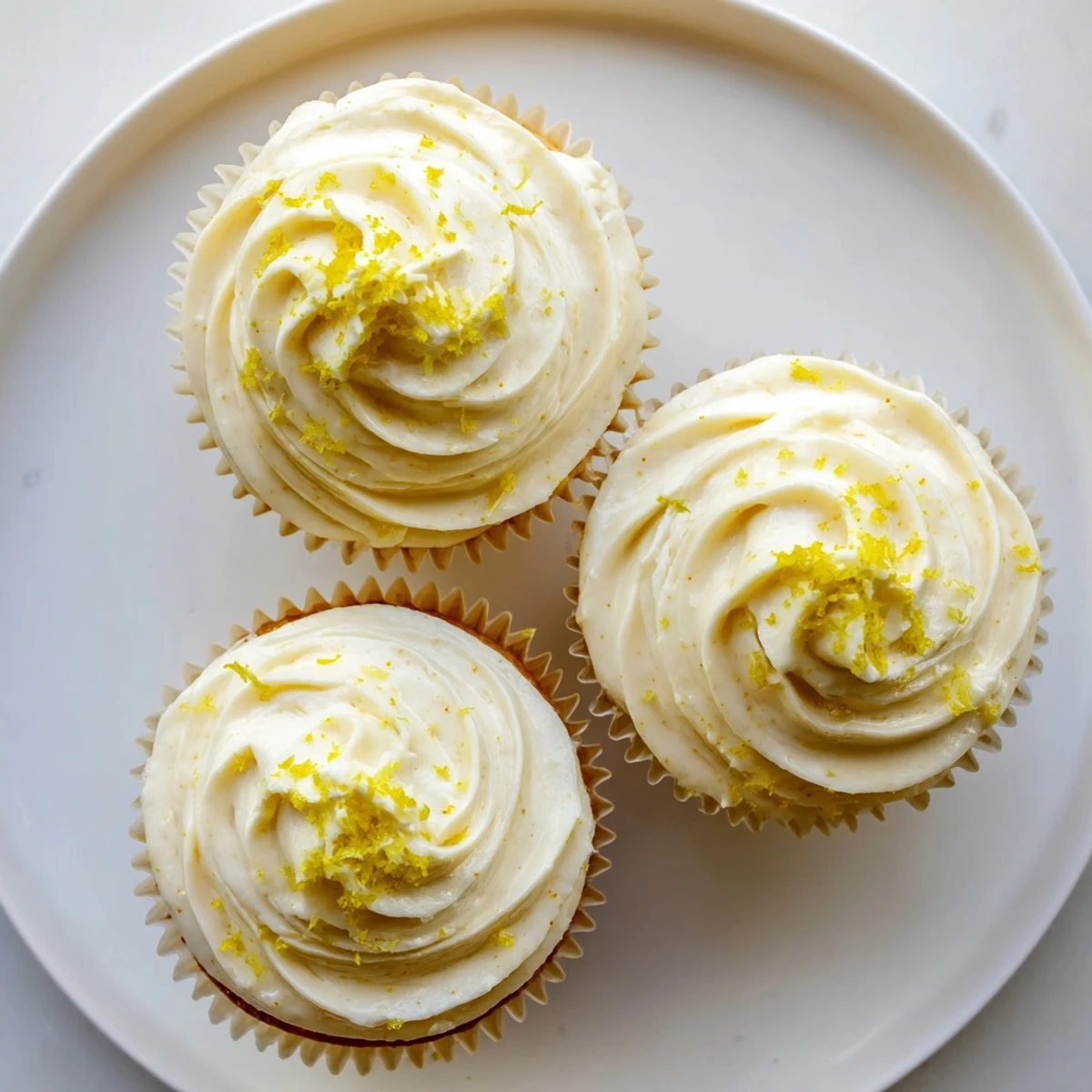 Twelve golden Limoncello cupcakes with creamy frosting, lemon zest garnish, ready for a spring dessert platter.