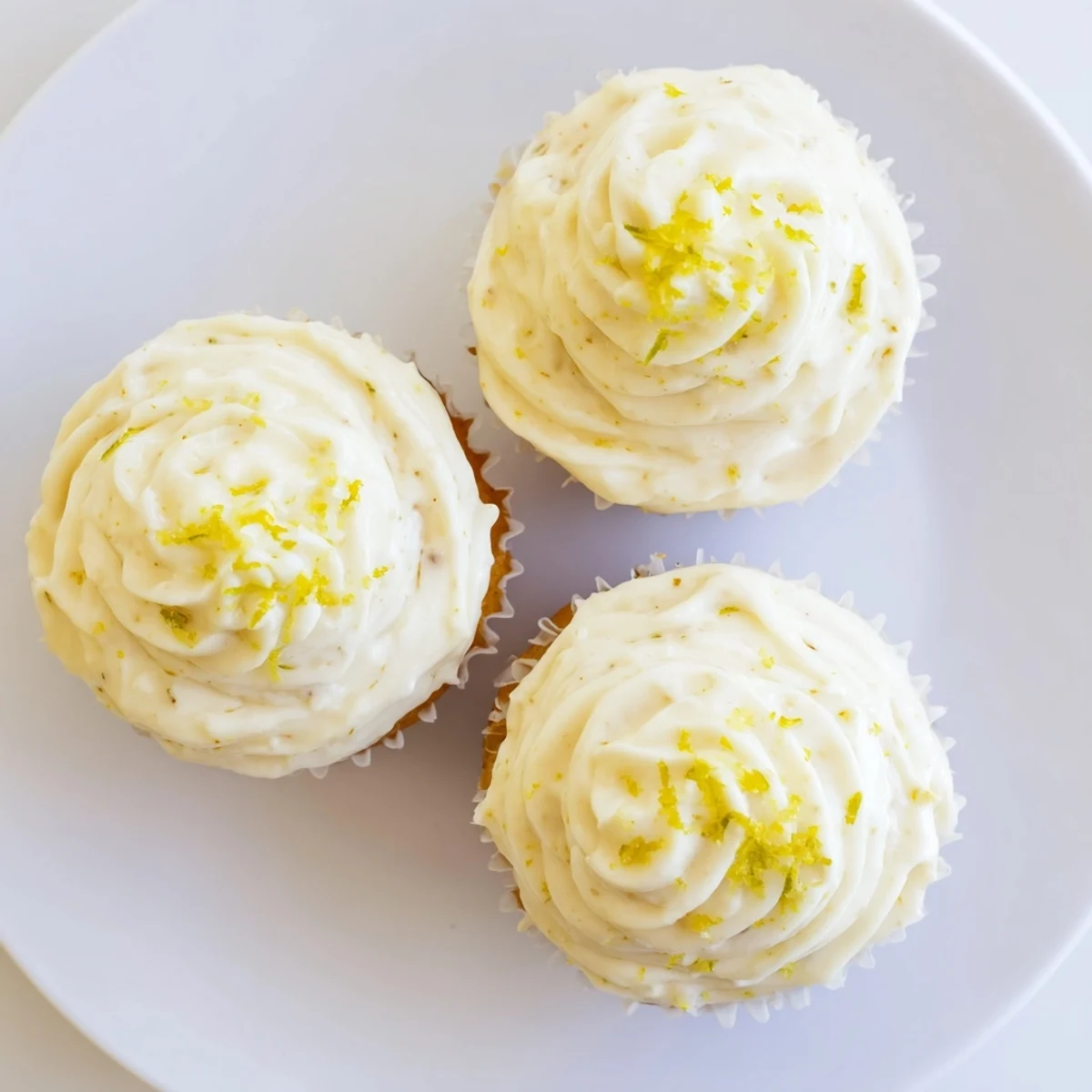 Moist Limoncello cupcakes topped with velvety frosting, bright lemon aroma, displayed on a marble surface.