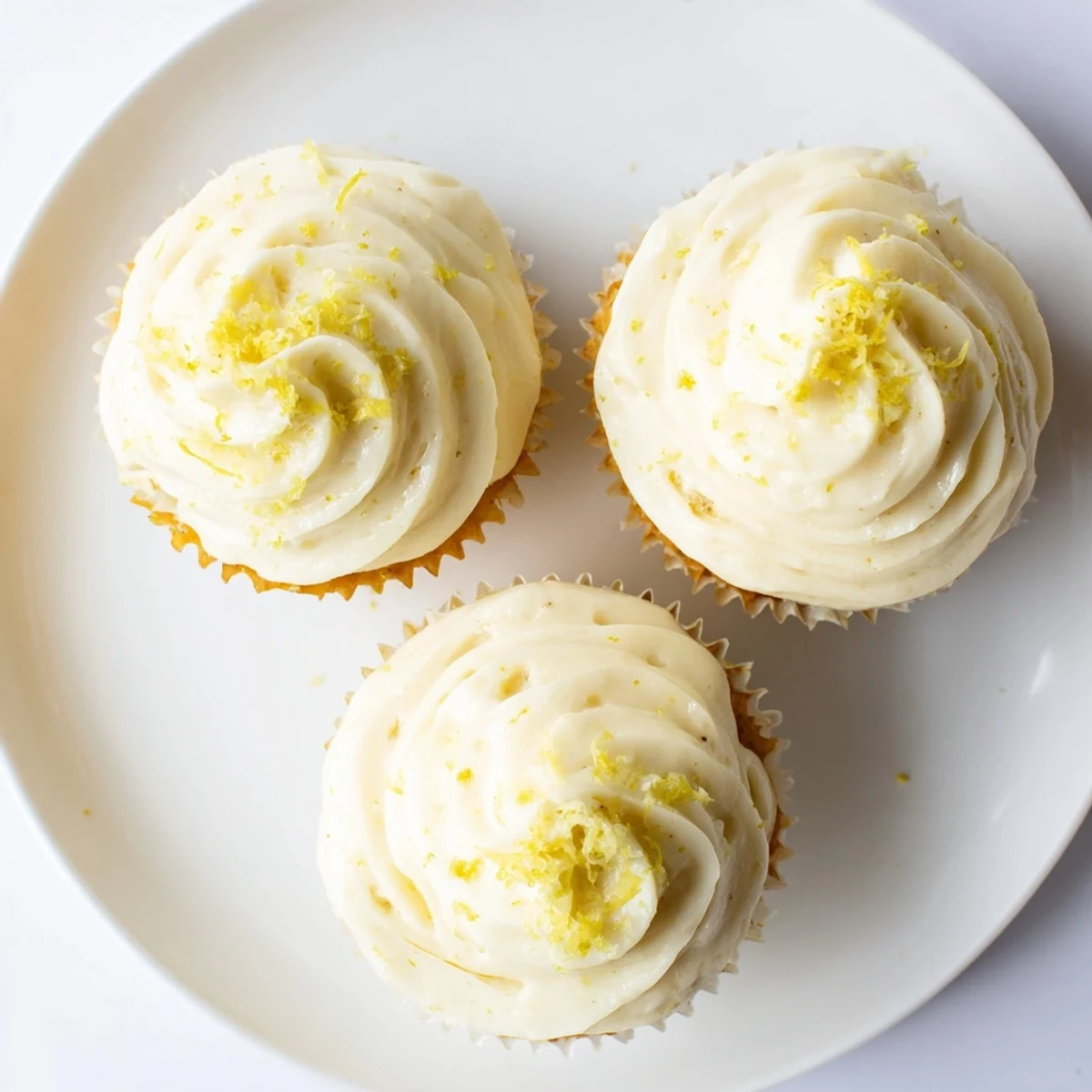 Limoncello cupcakes on a wire rack, lemon zest sprinkles, perfect for summer gatherings or brunch.