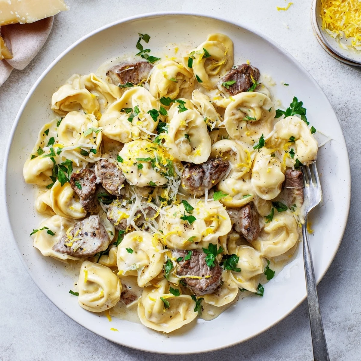 Golden cheese tortellini tossed with sliced seared steak in a rich cracked garlic cream sauce flecked with parsley and fresh lemon zest