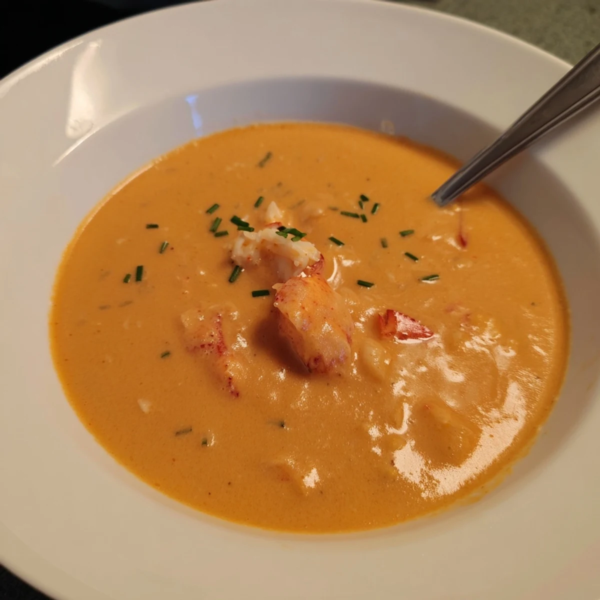 Creamy lobster bisque with tender chunks of lobster meat and fresh chive garnish