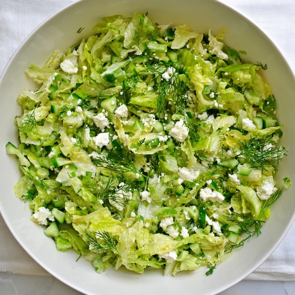 Vibrant bowl of Maroulosalata featuring shredded romaine, chopped dill and mint, topped with crumbled feta cheese