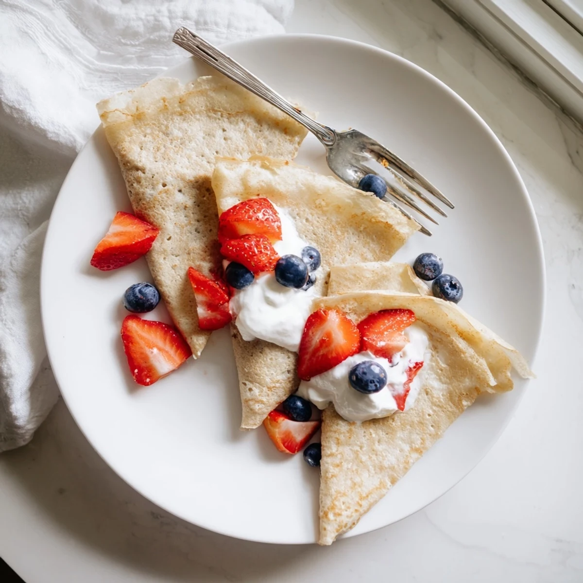 Golden brown healthy oatmeal crepes stacked high with maple syrup and dusting of powdered sugar