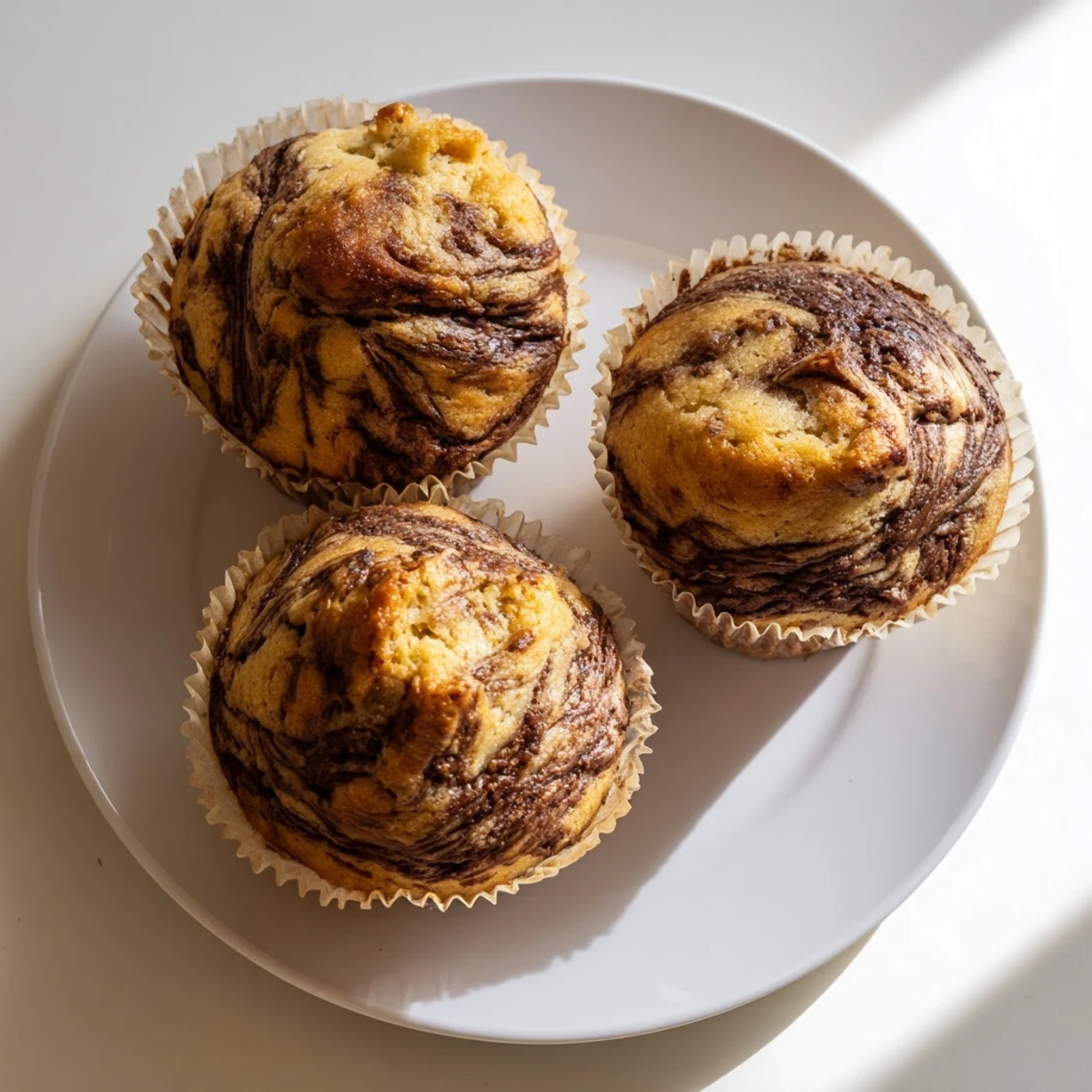 Moist banana muffins featuring rich Nutella swirls ready for breakfast or an indulgent afternoon snack