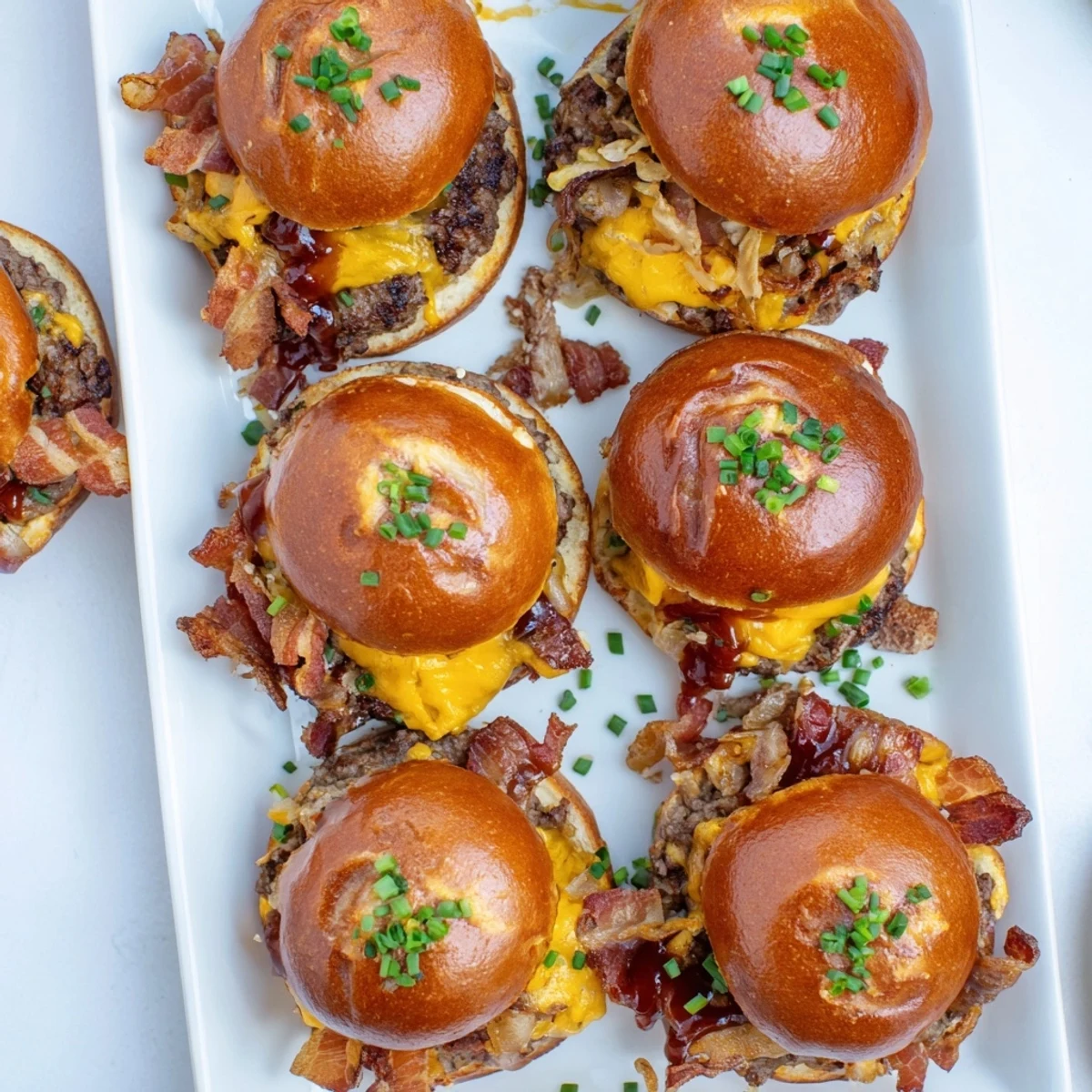 Golden pretzel bun sandwiches overflowing with seasoned beef patties, sharp cheddar, and smoky bacon in this Pretzel Cowboy Sliders recipe