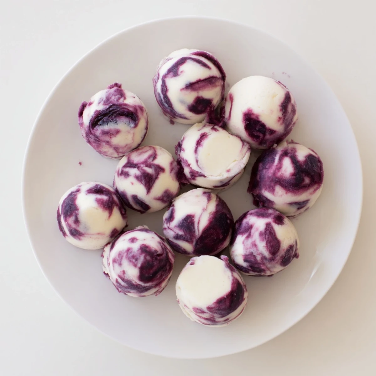 Creamy Greek yogurt bites featuring swirling blueberry compote patterns on a baking sheet