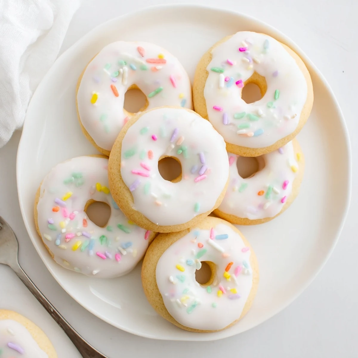 Soft Italian Easter Cookies topped with white icing and colorful pastel sprinkles on a serving platter