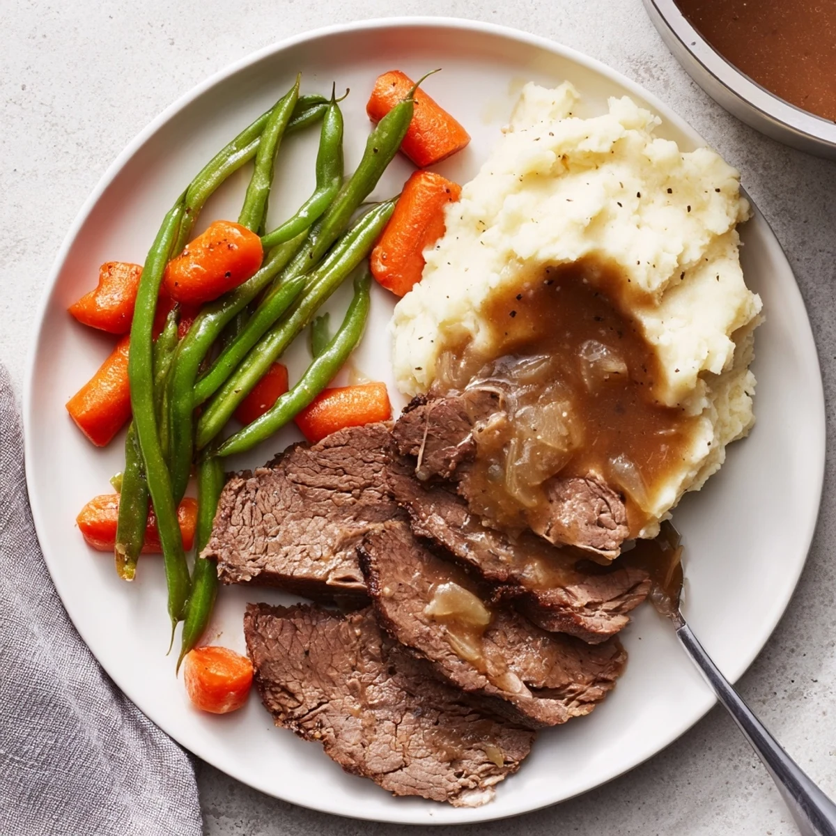 Comforting Southern style pot roast served with buttery mashed potatoes and fresh green beans on white plate