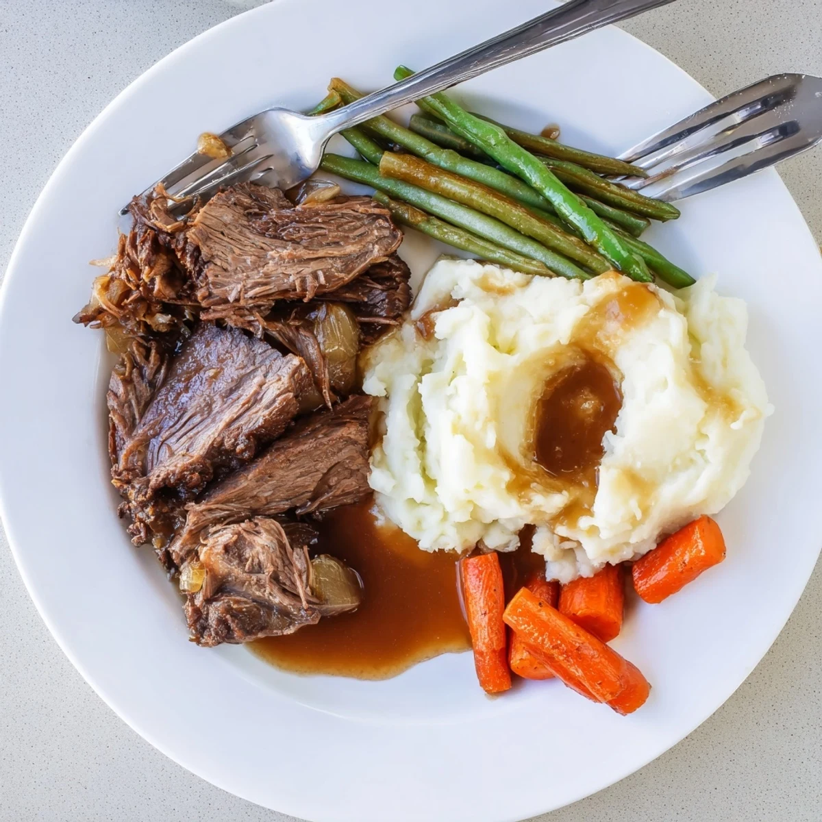 Fork-tender Southern style pot roast with caramelized vegetables and savory gravy drizzled over hearty sides