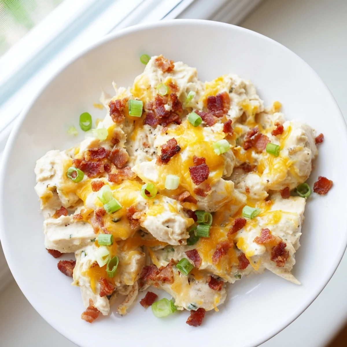 Bubbling crack chicken casserole dish garnished with green onions and extra bacon crumbles