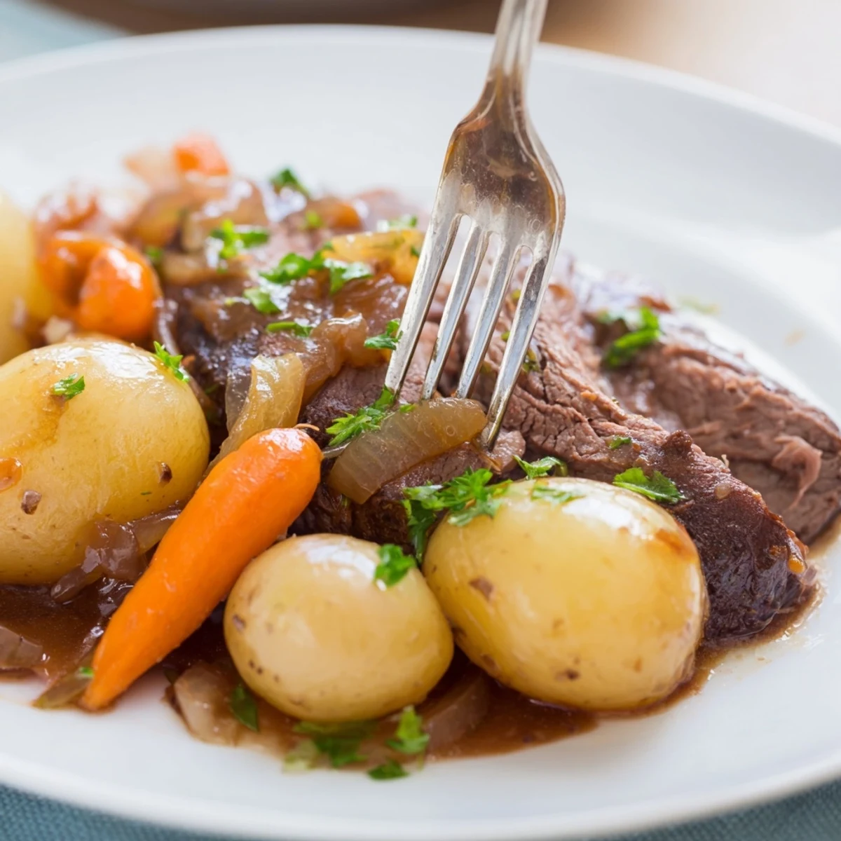 Hearty slow cooker steak and potatoes garnished with fresh parsley on a white plate
