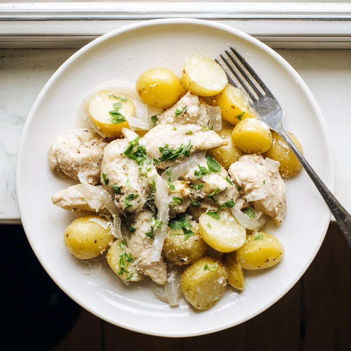 Hearty one-pot meal featuring juicy chicken breasts nestled beside baby potatoes in savory garlic parmesan glaze