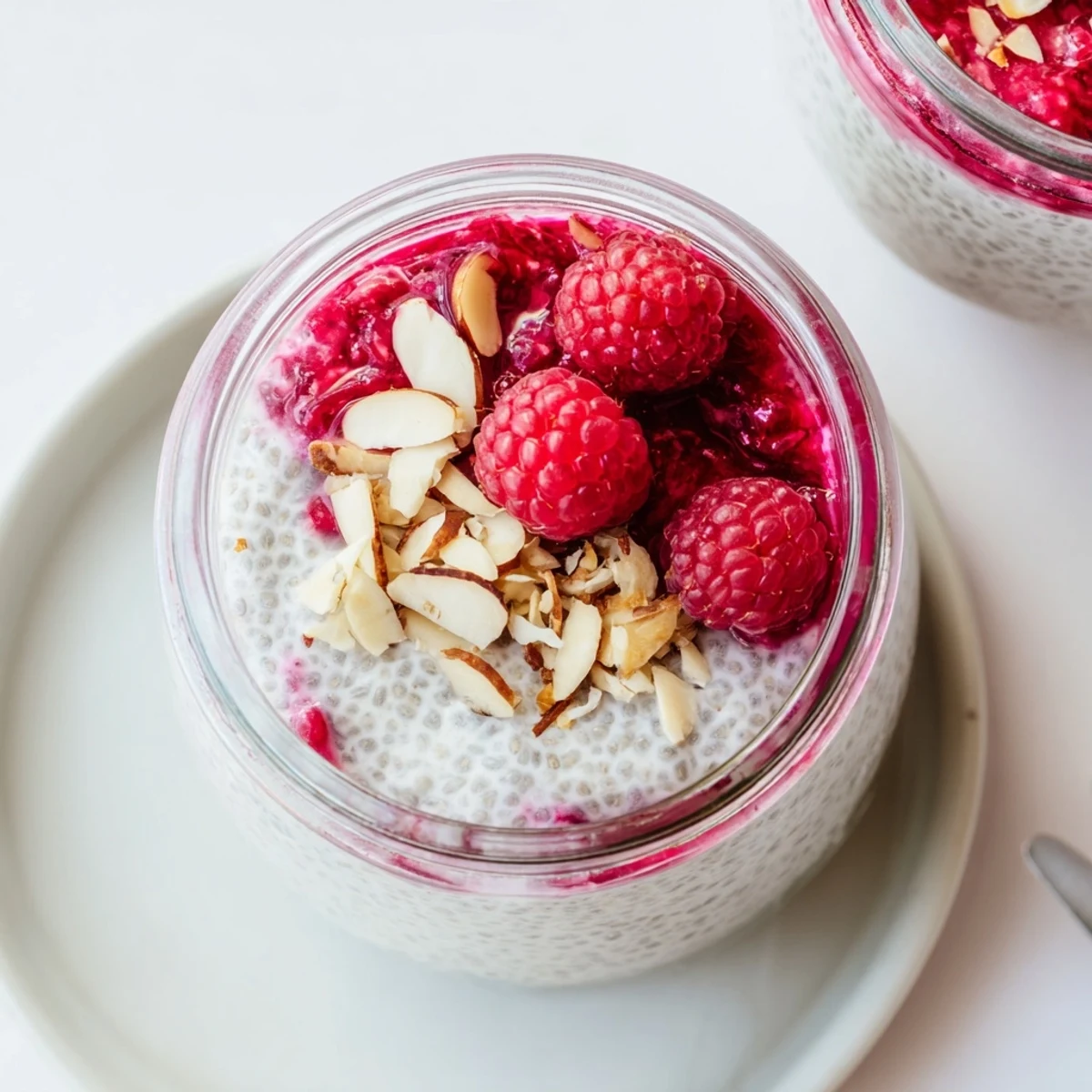 Vegan raspberry chia pudding sweetened with maple syrup topped with mint and fresh raspberries