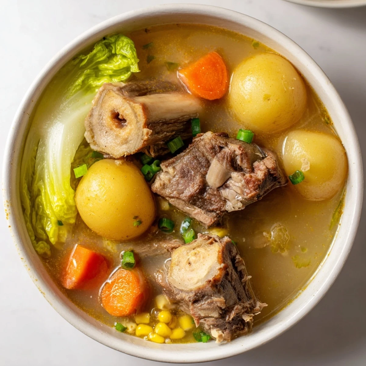 Steaming bowl of Filipino Bulalo with tender beef shank and vegetables in clear broth
