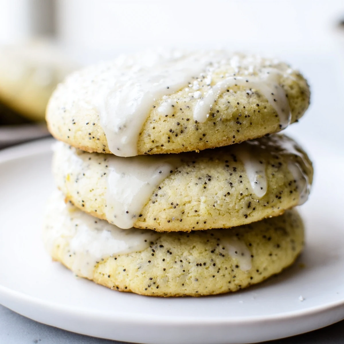 Lemon poppy seed cookies with golden edges and sparkly glaze on a white plate