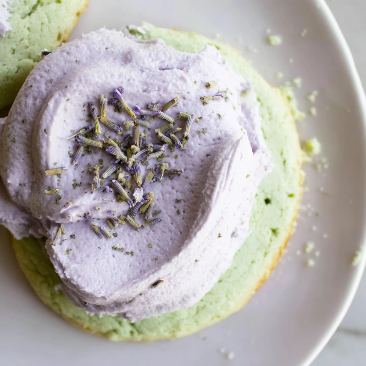 Elegant matcha sugar cookies topped with creamy purple lavender buttercream garnished with delicate buds