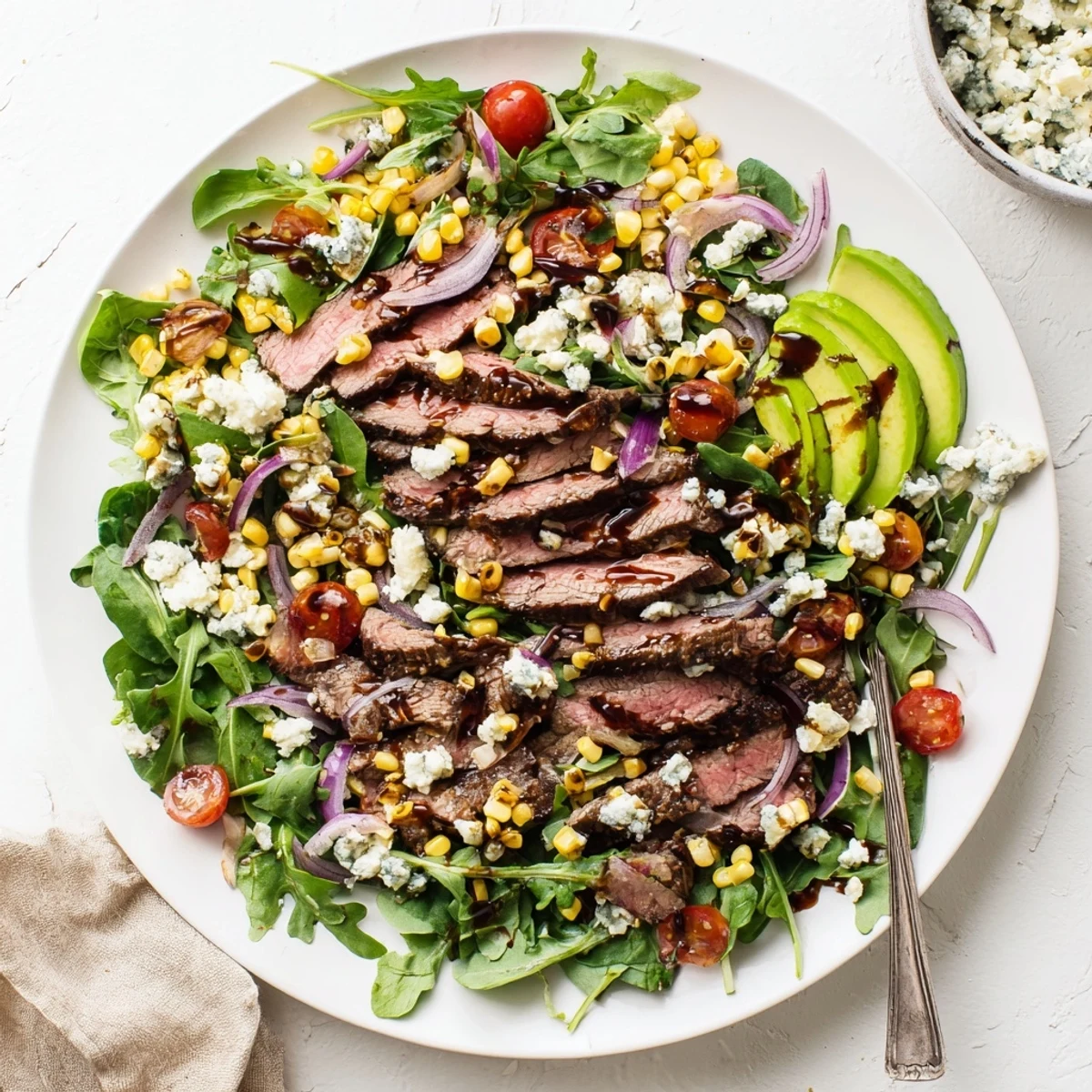 A generous platter of balsamic steak Gorgonzola salad drizzled with vinaigrette and avocado