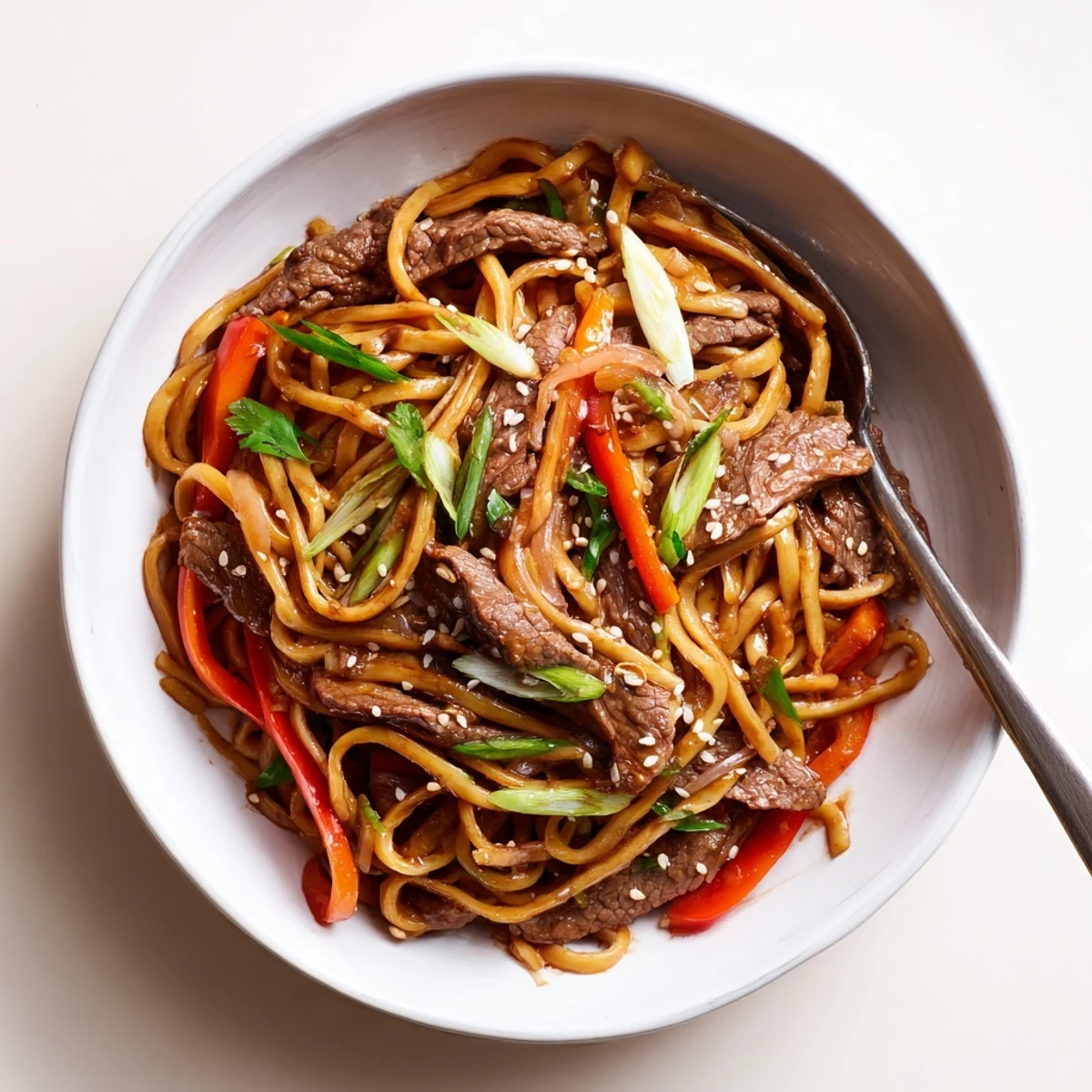 Sticky Beef Noodles glistening with glossy sauce, tossed with scallions and sesame