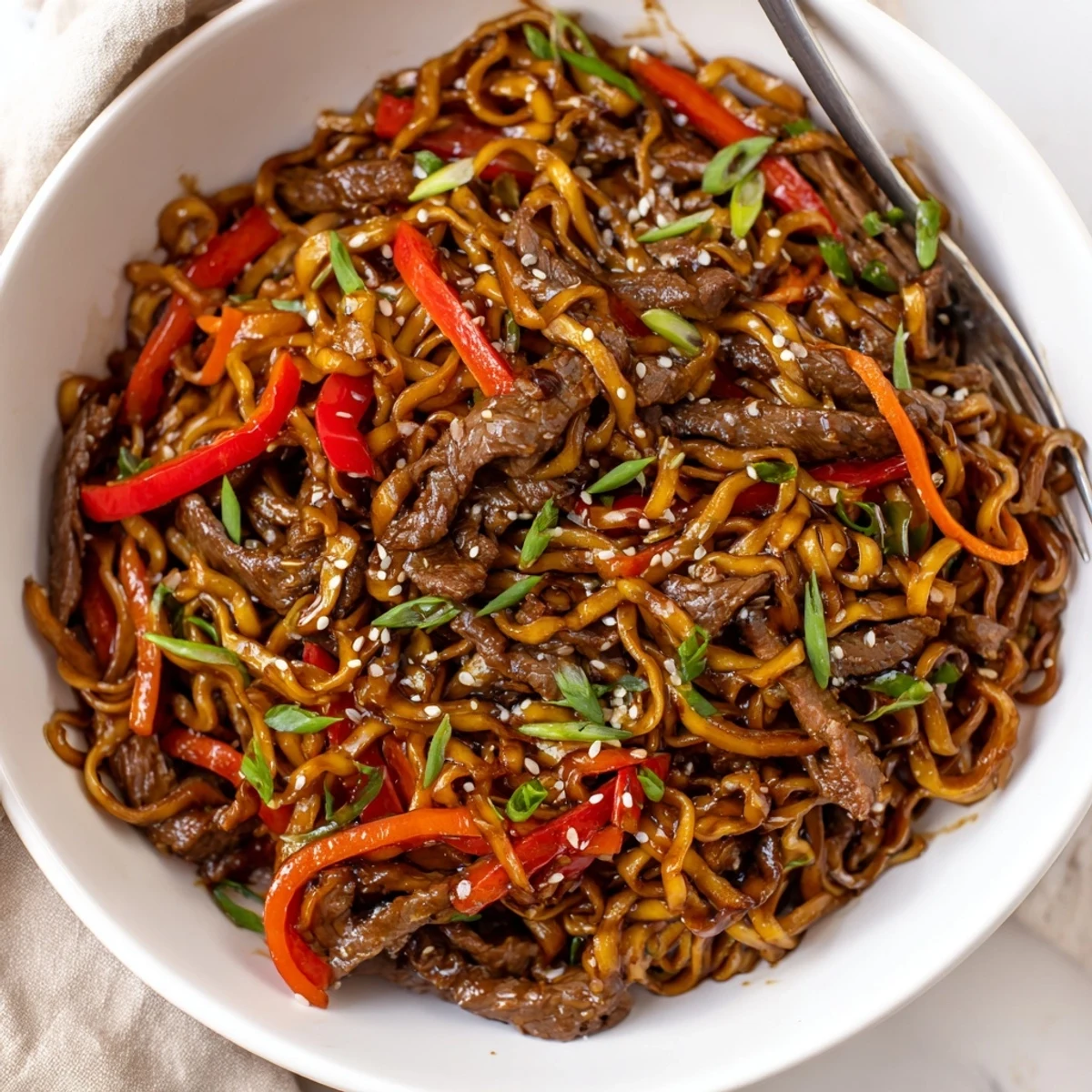 Plate of Sticky Beef Noodles steaming hot, tender beef and crisp peppers