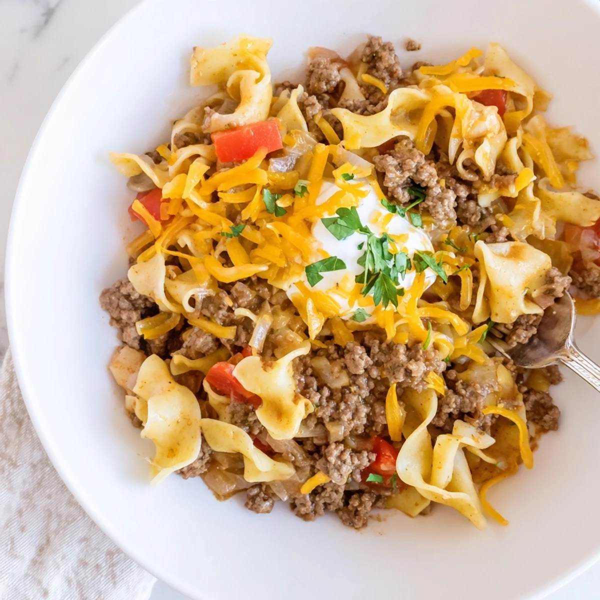 Spoonful of Beef Noodle Casserole showing tender meat, saucy noodles, parsley garnish