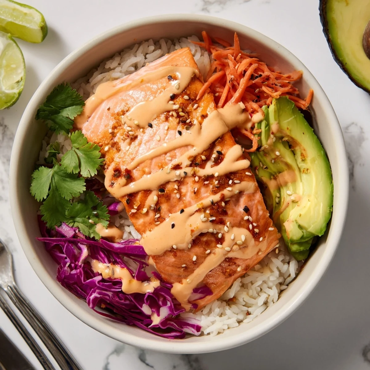 Bright Bang Bang Salmon Bowls Recipe with crunchy cabbage, avocado, and lime wedge