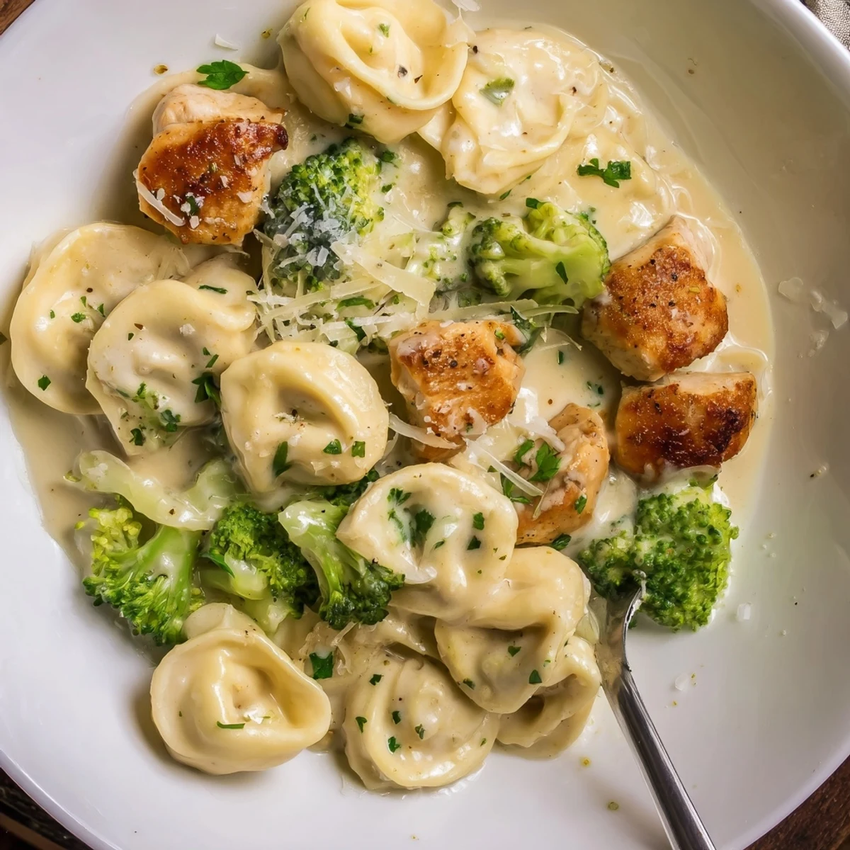 Steaming plate of silky tortellini and broccoli: Creamy Garlic Parmesan Tortellini Chicken Broccoli Recipe