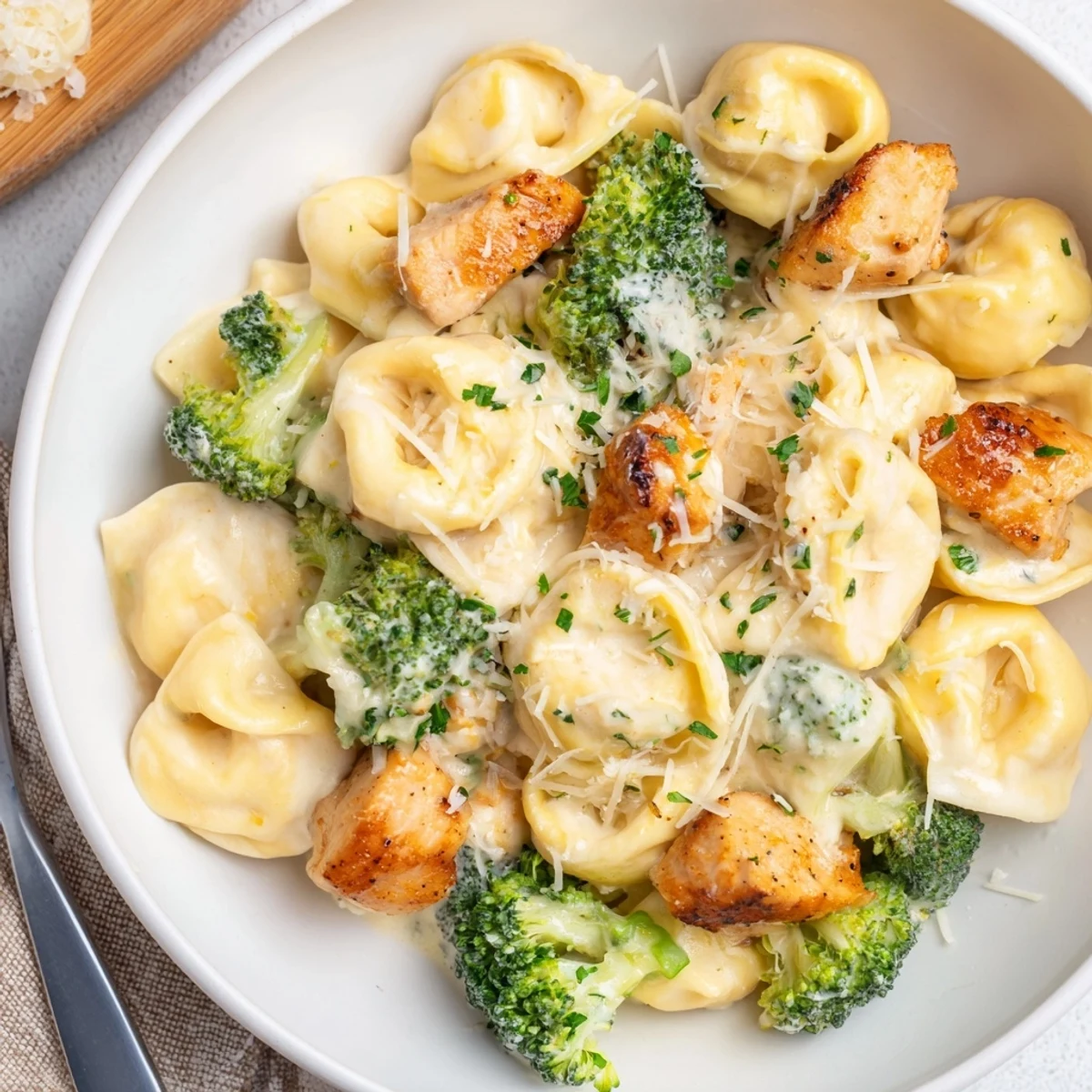 A hearty bowl of Creamy Garlic Parmesan Tortellini Chicken Broccoli Recipe, garnished with Parmesan
