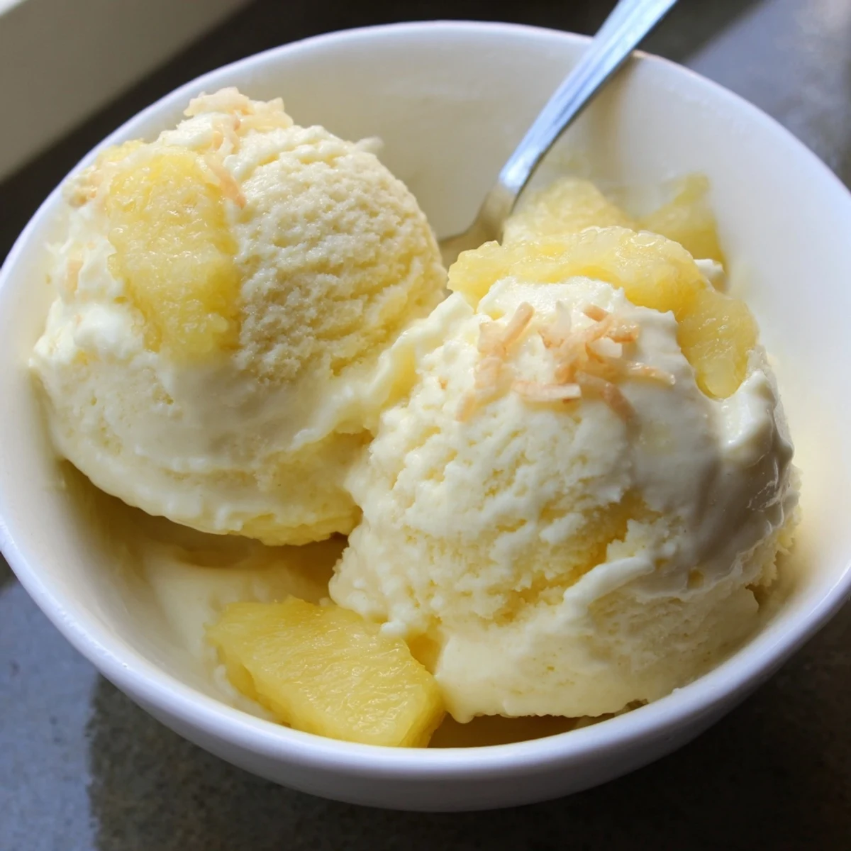 Creamy Pineapple Ice Cream spoonful glistening with syrupy juice, chilled summer treat