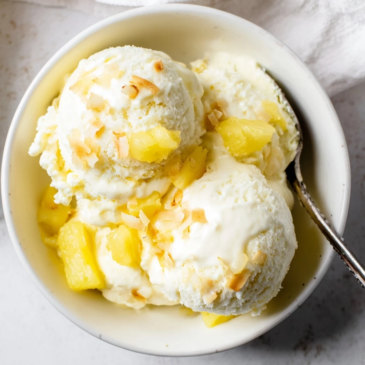 Scoops of Creamy Pineapple Ice Cream topped with toasted coconut flakes