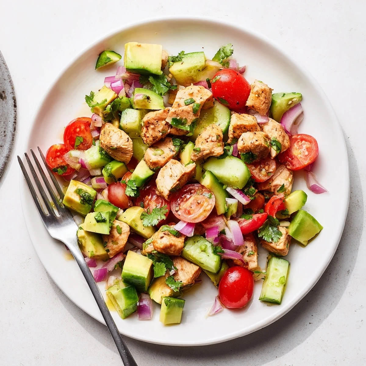 Grilled chicken chunks tossed with ripe avocados, cherry tomatoes, and crisp cucumber in healthy avocado chicken salad