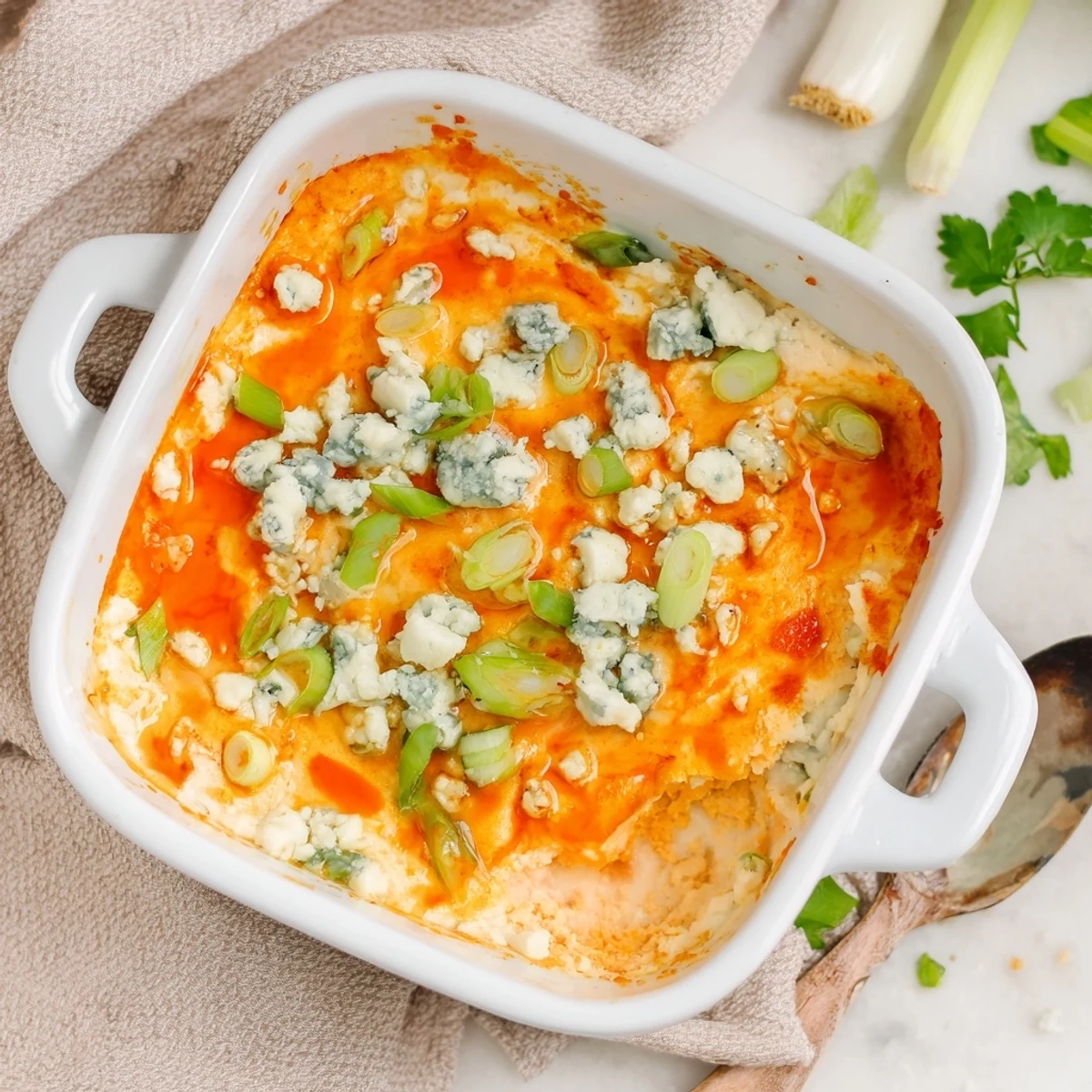 Golden bubbly cheesy white bean buffalo dip fresh from the oven topped with green onions