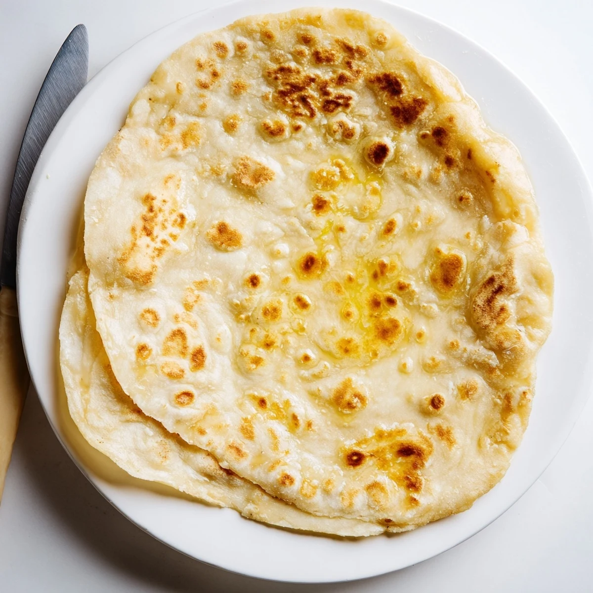 Warm Turkish Bazlama bread stack brushed with olive oil on wooden board