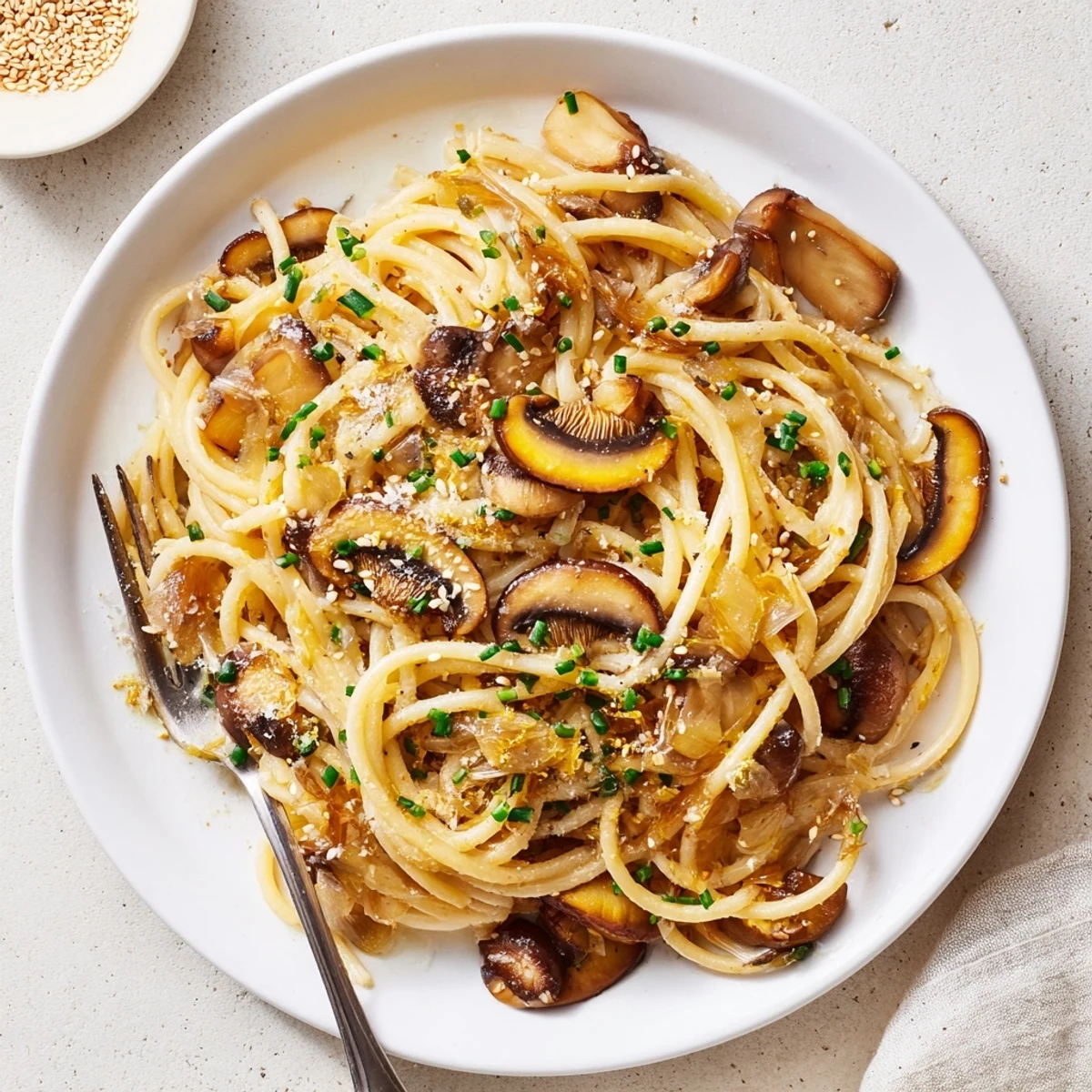 Creamy miso mushroom pasta garnished with chives parmesan and sesame seeds on white plate